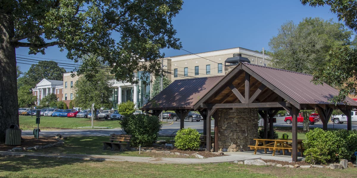 A park pavilion with a brown metal roof, stone pillars, and a picnic table